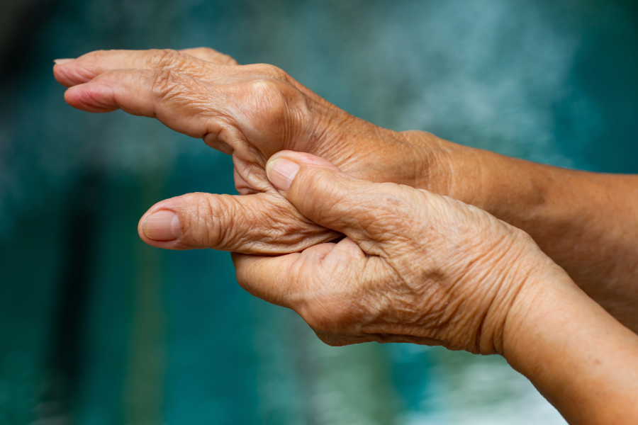 A close up of hands. The left hand holds the right while pressing into the area between the thumb and index finger.